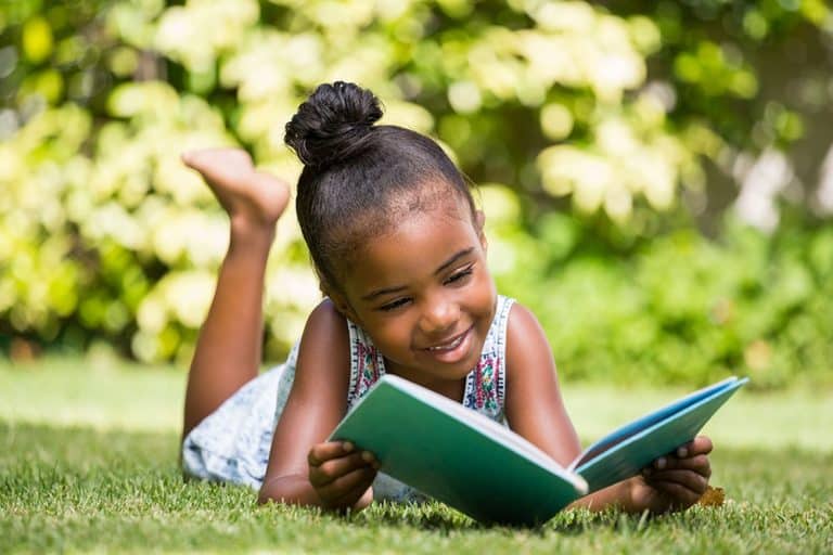 Kind leest boek in de tuin