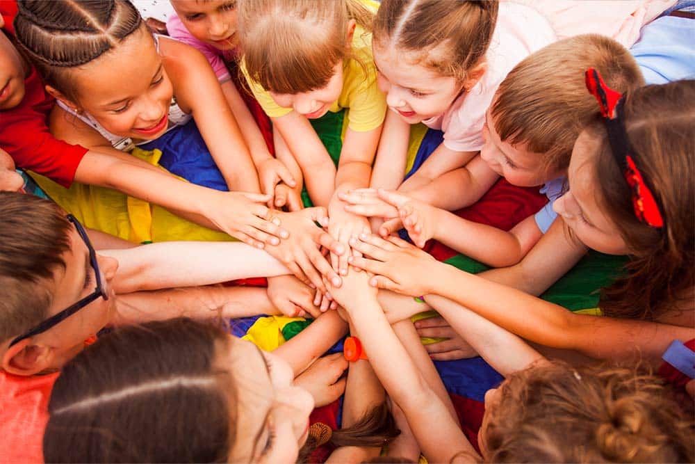 Een groep kinderen legt hun handen op elkaar