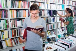 Een lachende tiener leest een boek in de bibliotheek