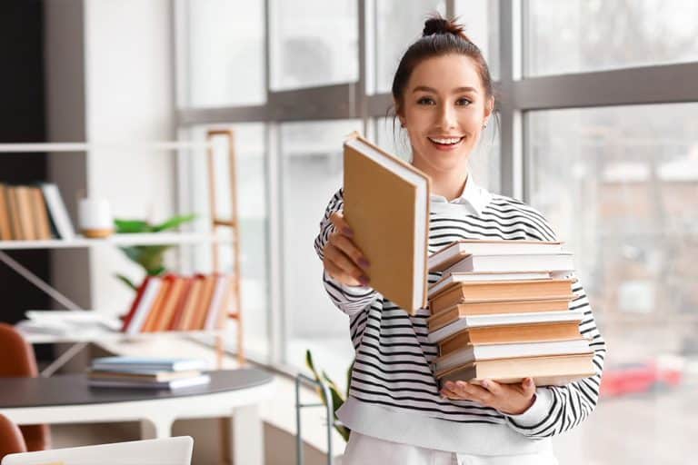 Een jonge vrouw met een stapel boeken in haar hand