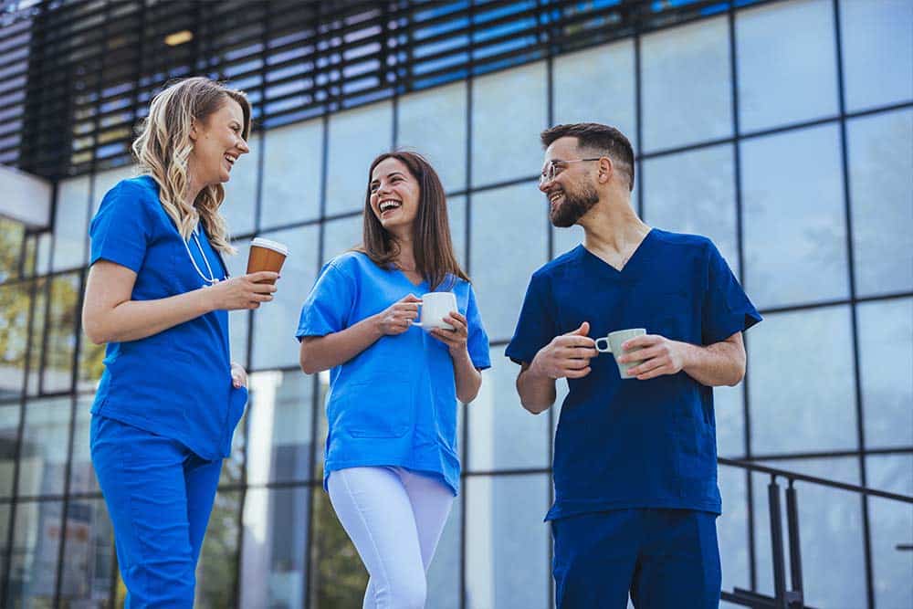 Drie collega's uit de zorg drinken een kopje koffie tijdens een wandeling