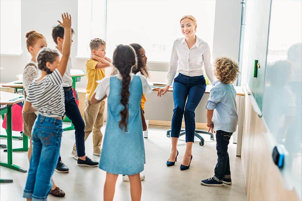 Een groepje kinderen staat in de klas om de juf heen