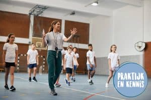 Een leerkracht loopt met kinderen in de gymzaal