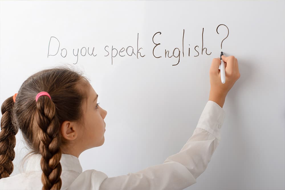 Meisje schrijft op het bord: Do you speak English?