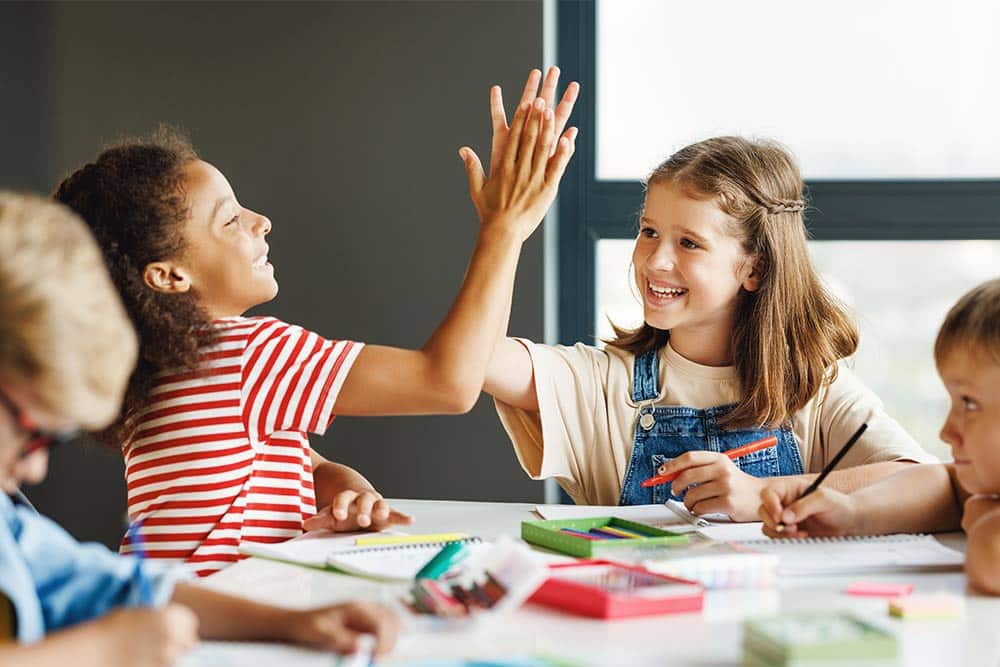 Twee kinderen geven elkaar in de klas een high five